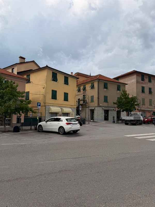 Piazza di Pedemonte con palazzine gialle e ocra, persiane verdi e tetti in cotto