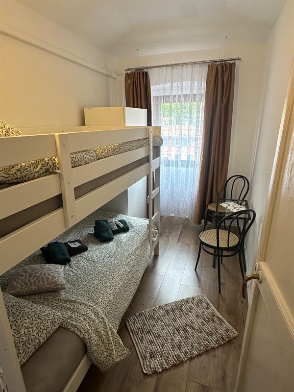 Camera con letto a castello, asciugamani sul letto, sedie in legno curvato e tavolino