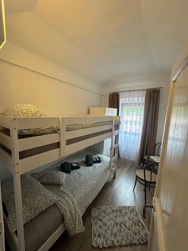 Camera vista dalla finestra a triplo vetro, con letto a castello e due sedie
